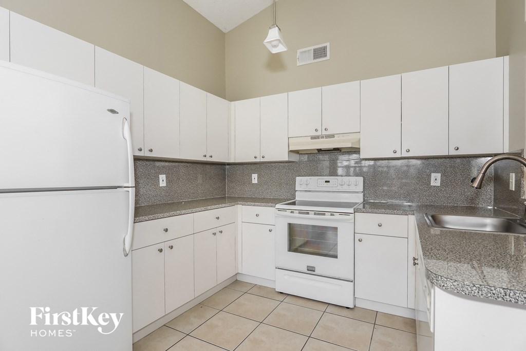 a kitchen with white cabinets and appliances and a sink