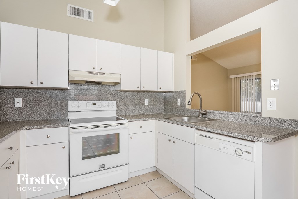 a white kitchen with white appliances and granite counter tops