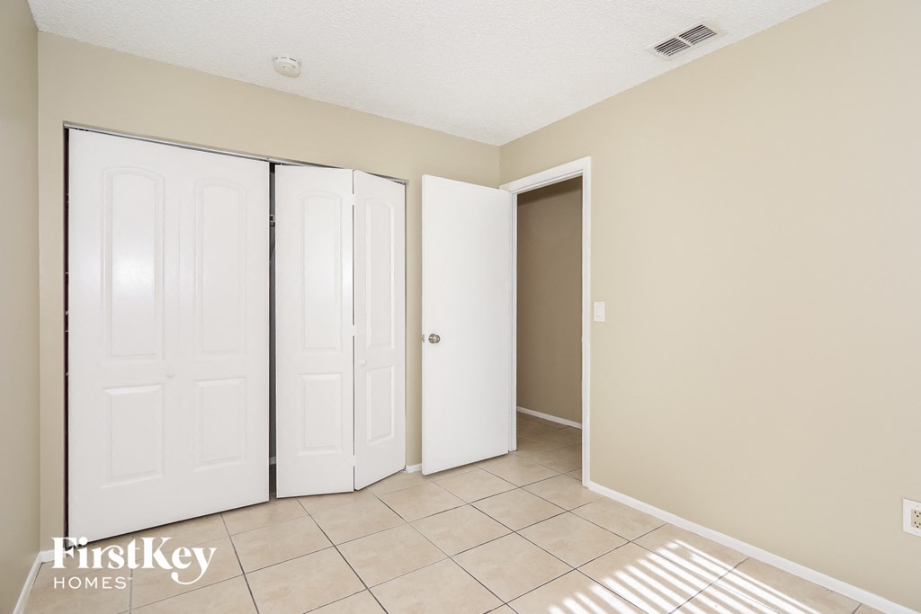 a bedroom with two closets and a tiled floor and two doors