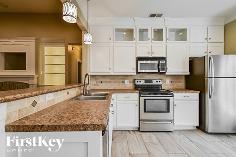 A kitchen with a granite counter top and stainless steel appliances.