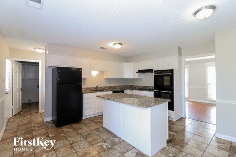 a kitchen with white cabinets and a black refrigerator