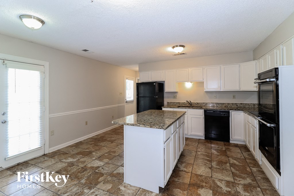 a kitchen with white cabinets and a black refrigerator