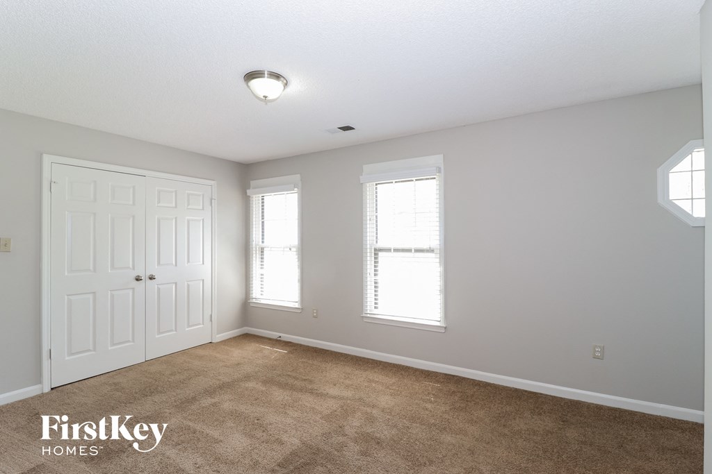 a bedroom with a carpeted floor and two windows and a white door
