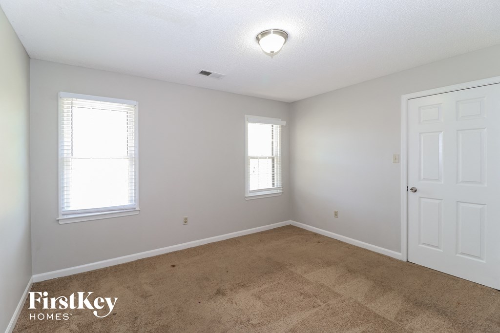 a bedroom with a carpeted floor and a white door and window