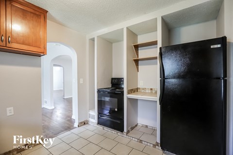 A black refrigerator sits in a kitchen with a black stove and oven.