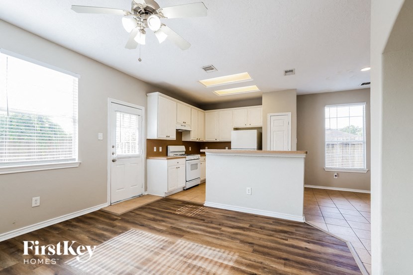 an empty kitchen and living room with a ceiling fan