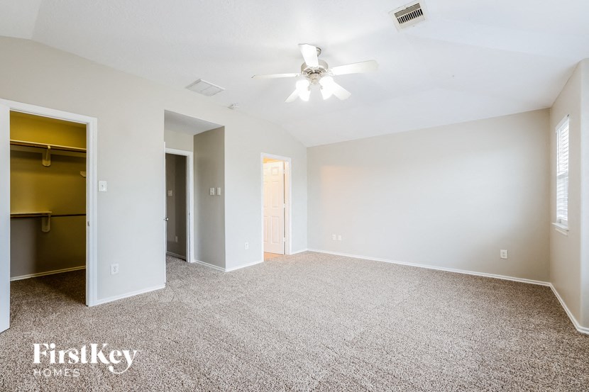 a spacious living room with carpet and a ceiling fan