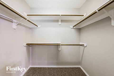 a spacious walk in closet with empty shelves and hooks