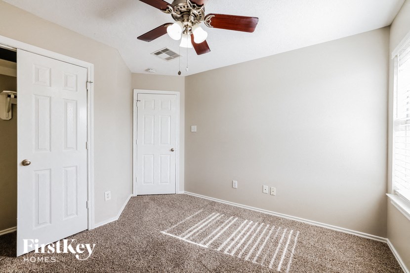 a carpeted living room with a ceiling fan and white doors