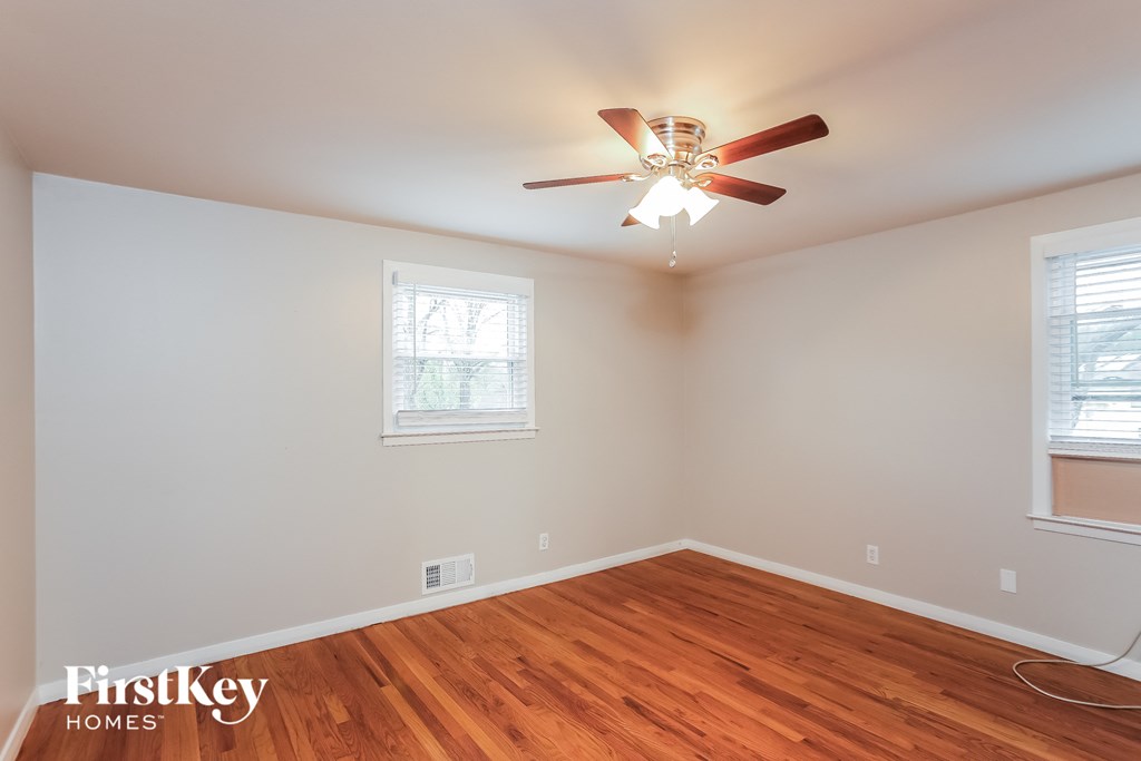 a bedroom with wood floors and a ceiling fan