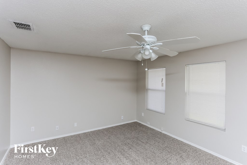 a bedroom with a ceiling fan and two windows