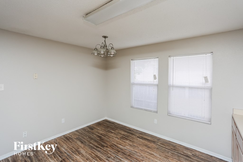 a living room with wood flooring and two windows and a chandelier