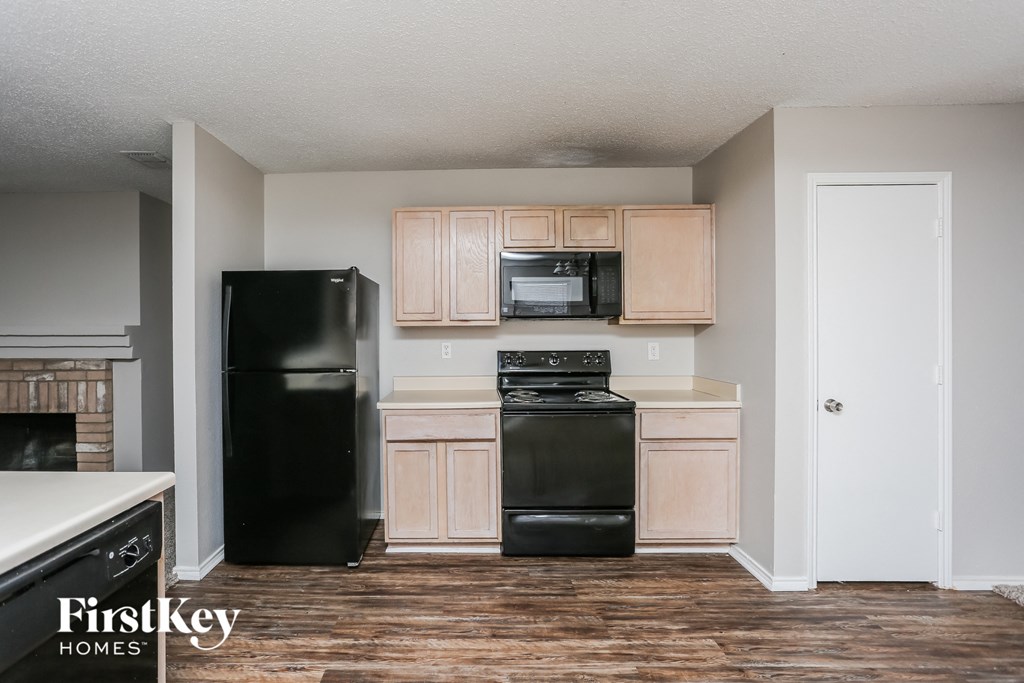 a kitchen with black appliances and wood flooring