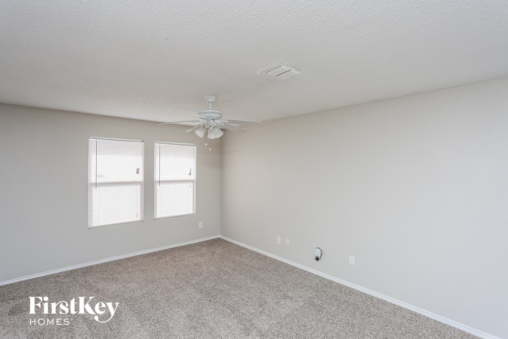 a bedroom with white walls and a ceiling fan
