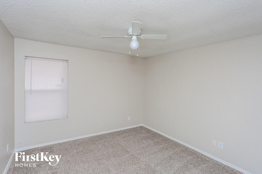 an empty room with a ceiling fan and a window