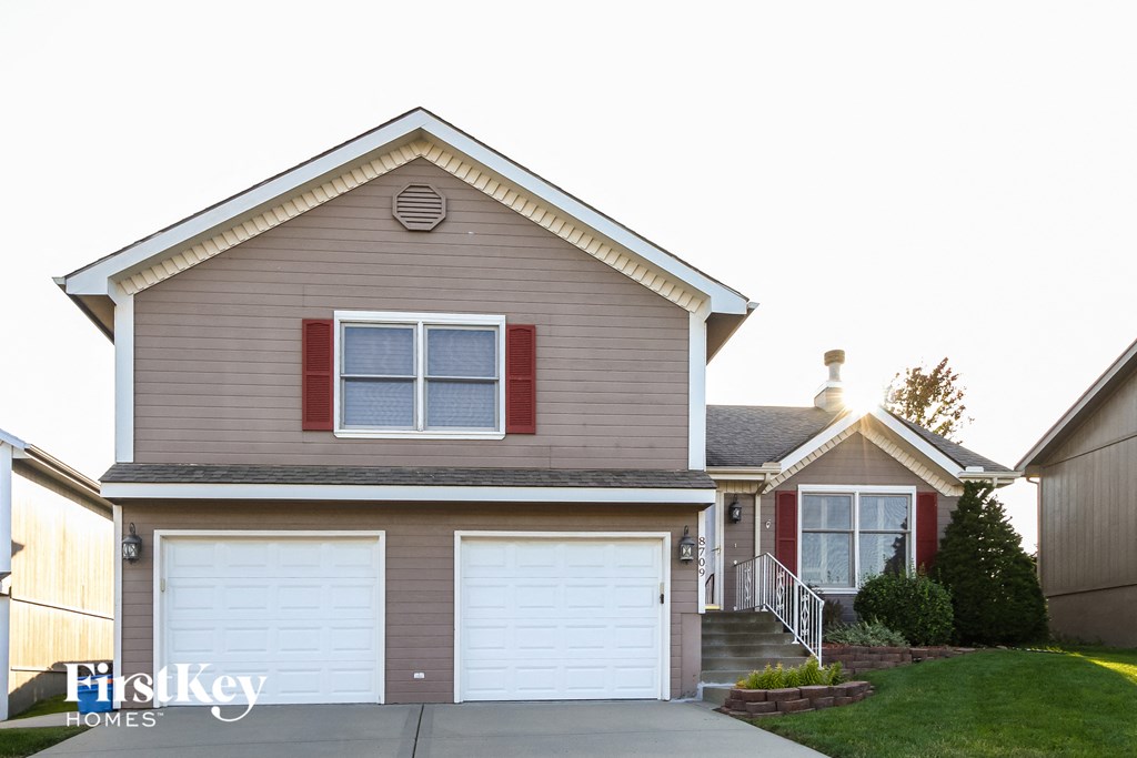 A two-story house with a garage and a red window.