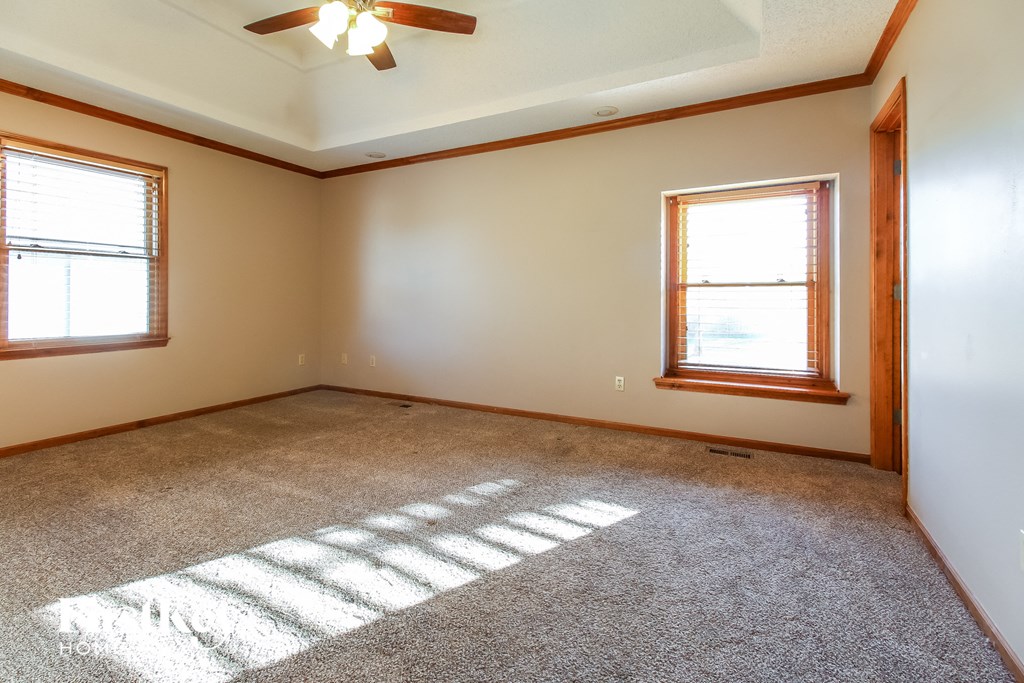 A room with a carpeted floor and a ceiling fan.