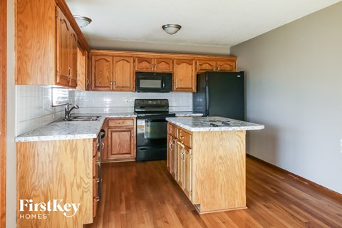 A kitchen with wooden cabinets and a black refrigerator.