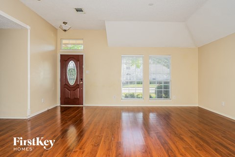 A room with a wooden floor and a red door.