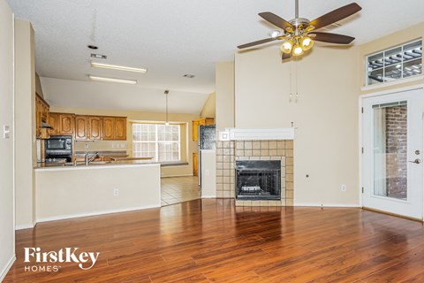 A spacious living room with a fireplace and a ceiling fan.