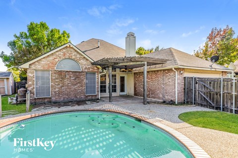 A brick house with a pool in the backyard.