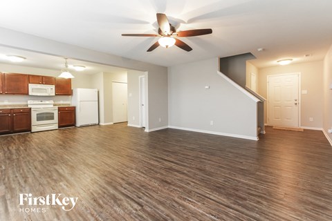 A spacious living room with a wood floor and a ceiling fan.