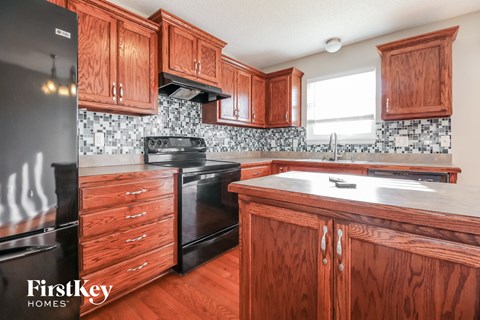 A kitchen with wooden cabinets and a black fridge.