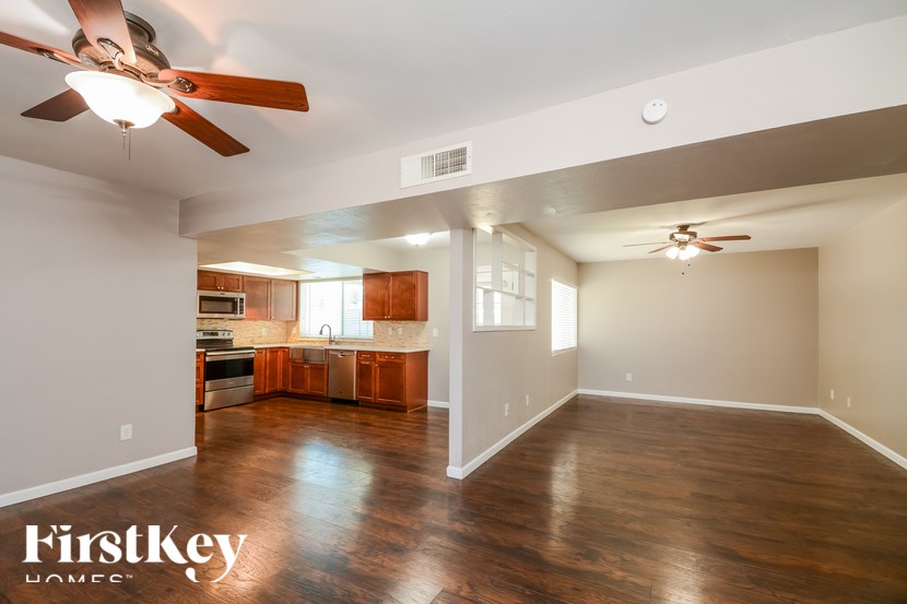 A spacious kitchen and living room with wooden floors and a ceiling fan.