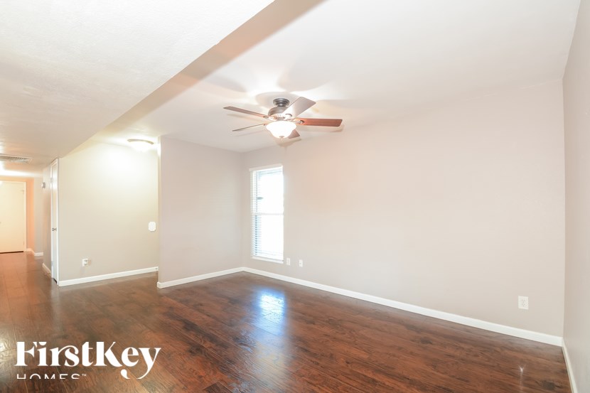A spacious room with a ceiling fan and wooden flooring.