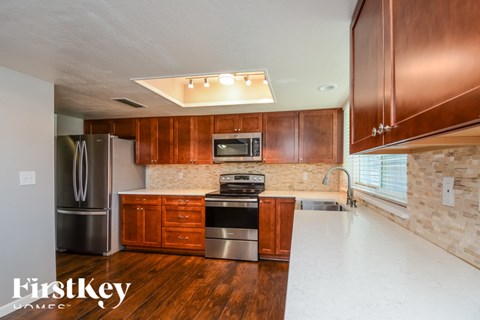 A kitchen with wooden cabinets and a stainless steel refrigerator.