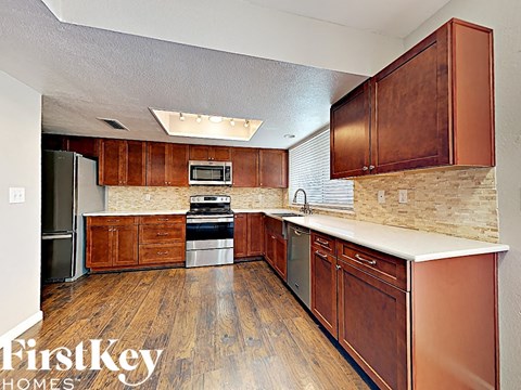 A kitchen with wooden cabinets and a stone backsplash.
