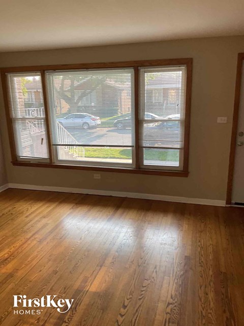 an empty living room with a hard wood floor and large windows