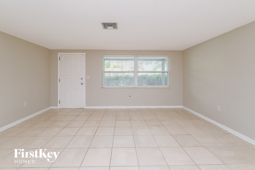 A room with a white door and a window with a view of trees and a fence.