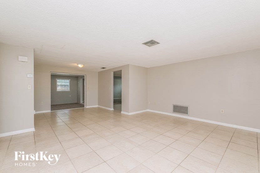 A spacious room with a tiled floor and a doorway leading to another room.