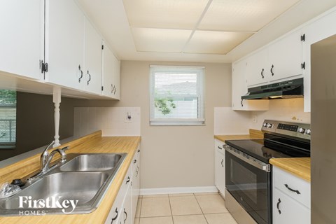 A kitchen with white cabinets and a stainless steel sink.