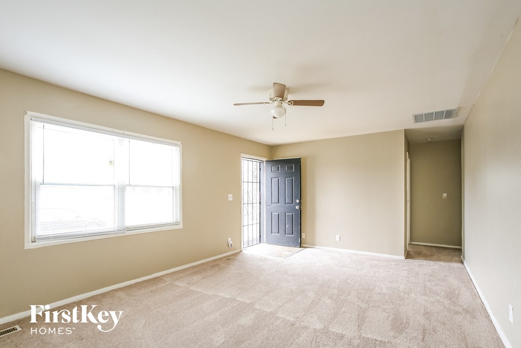 A spacious room with a ceiling fan and a door at the end.