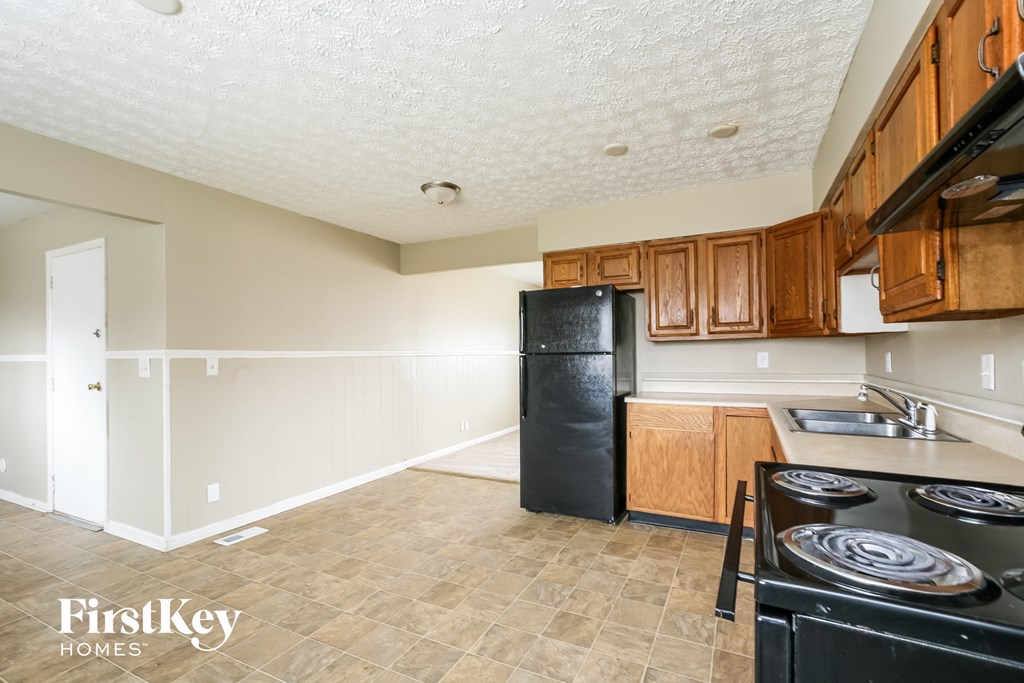 A kitchen with a black fridge and stove top oven.