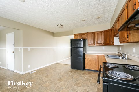 A kitchen with a black fridge and stove top oven.
