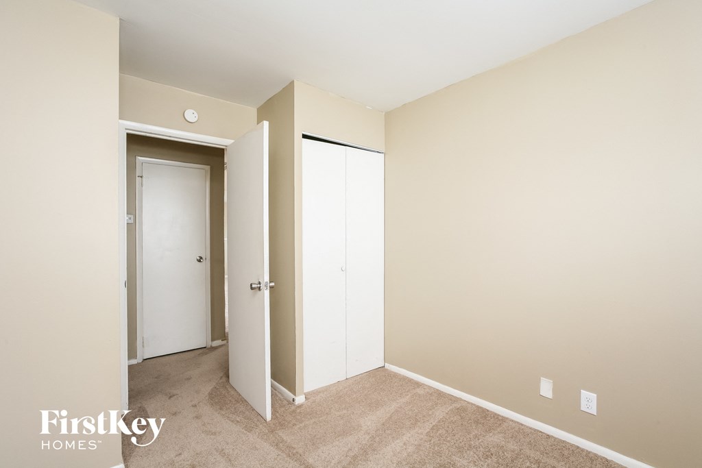 A bedroom with a beige wall and a white door.