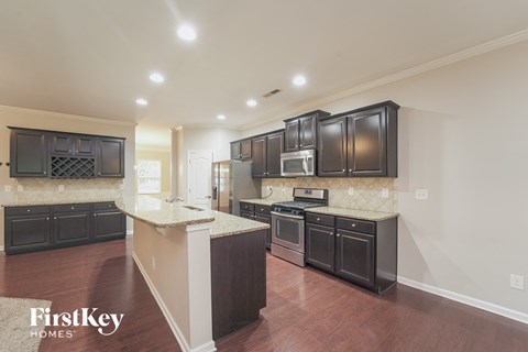 a kitchen with black cabinets and white counter tops and a wooden floor