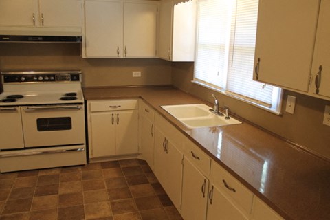 A kitchen with white cabinets and a brown countertop.