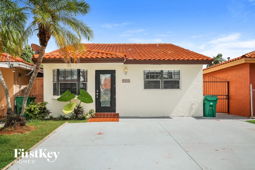 A house with a red tile roof and a black door is for sale.