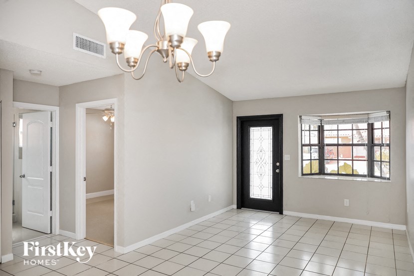 A well-lit room with a chandelier and a view of the outside through the window.