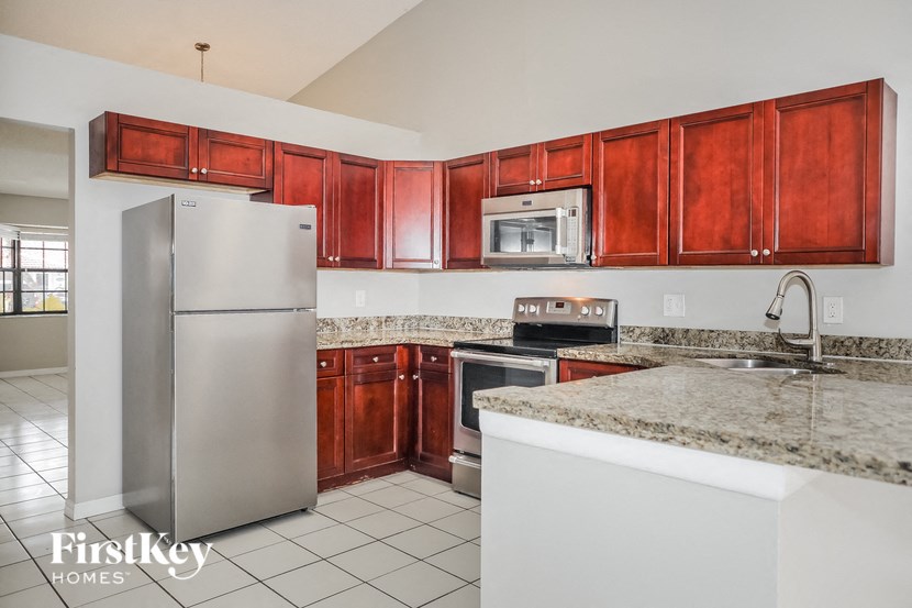 A kitchen with a refrigerator, microwave, oven, and sink.