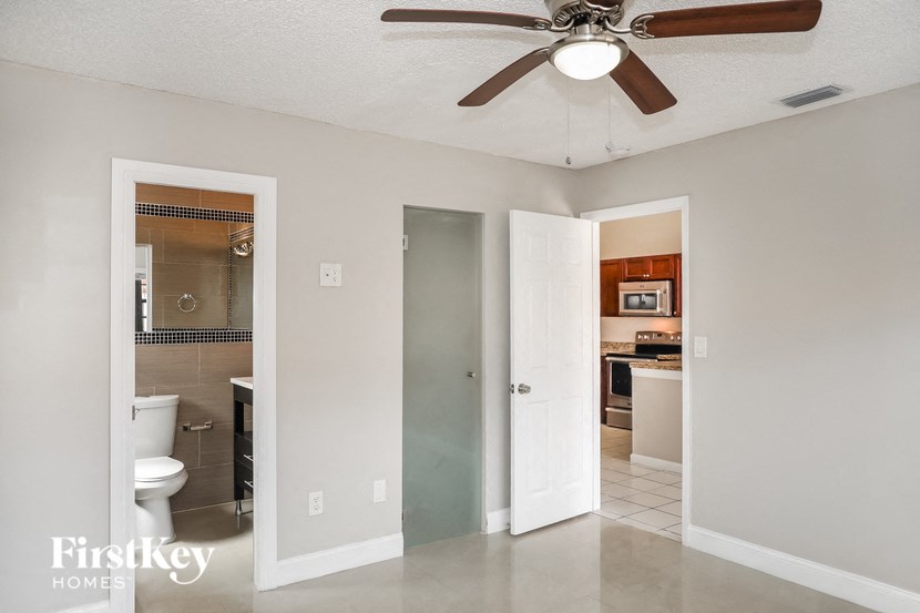 A room with a ceiling fan and a door leading to a kitchen.