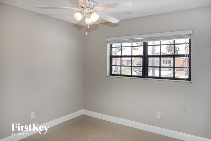 A room with a ceiling fan and a window with blinds.