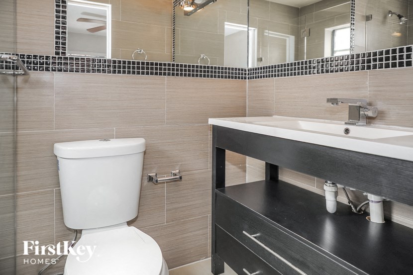 A bathroom with a toilet, sink, and mirror.