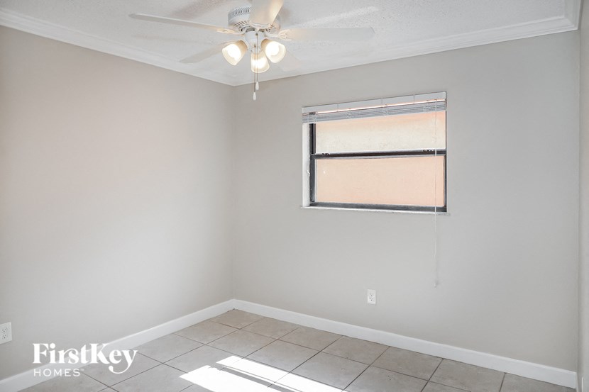 A room with a ceiling fan and a window with blinds.