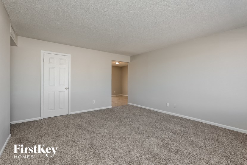 a spacious living room with carpet and a white door
