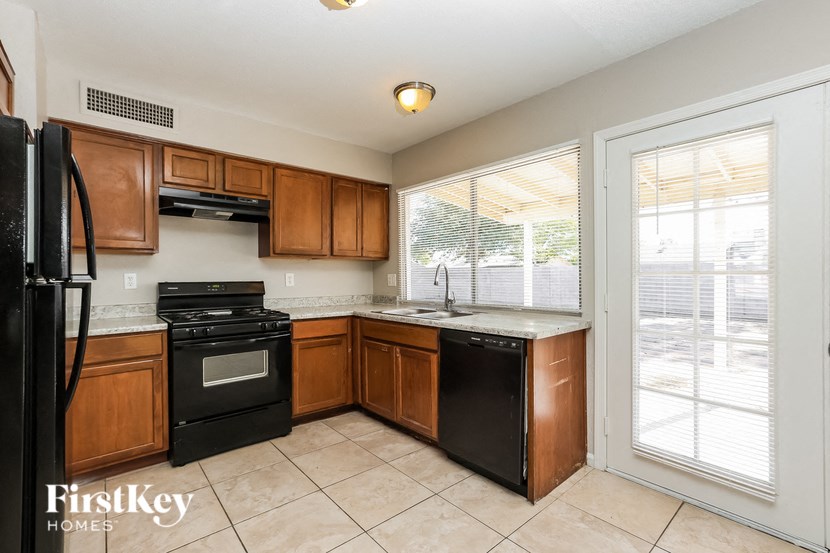a kitchen with wooden cabinets and black appliances and a window